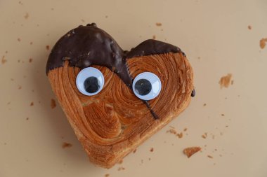 Yaratıcı çılgın gözler Heart 'ın üzerinde. Bej arka planda koyu çikolatalı kruvasan ve fotokopi alanı. Puf puf yeni moda tatlı pastanesi. Kremalı hamur deneyi 