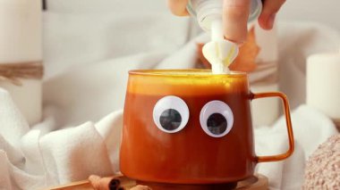 Krem şantili komik cadılar bayramı dekorasyonu suratı ve sabah kahvesini acılı balkabağı latte ile ısıtmak. Cadılar Bayramı için sonbahar içkileri Şükran Günü Tatil içeceği Sonbahar baharlı tarçın