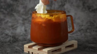 Krem şantili, mevsimlik kremalı ve tarçınlı kakao kahvesi ekliyorum. Sıcak turuncu bardak Şükran Günü ve Hello Fall Cadılar Bayramı konsepti. Karanlık arka planda sonbahar tatilini kutluyoruz.. 