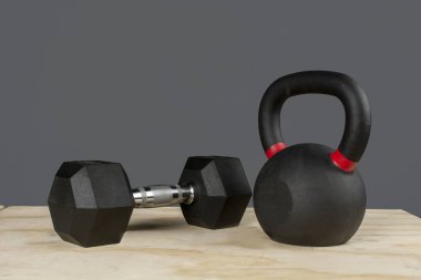 Dumbbell y Kettlebell ayık caja de madera y fondo gris