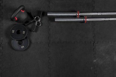 Barras, Discos, Seguros, Kettlebell y Dambıl de crossfit sobre piso negro de goma
