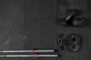 Barras, Discos, Seguros, Kettlebell y Dambıl de crossfit sobre piso negro de goma