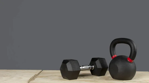 Dumbbell y Kettlebell ayık caja de madera y fondo gris