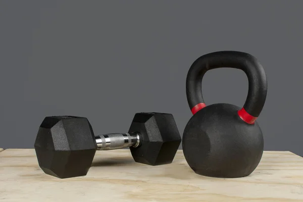 Dumbbell y Kettlebell ayık caja de madera y fondo gris