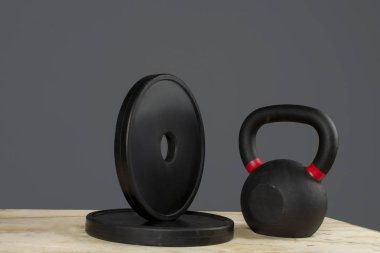 Diskolar de peso y kettlebell ayık caja de madera y fondo gris