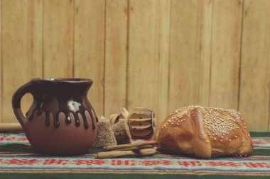Pan de muerto cortado con taza de cafe, canela y piloncillo en fondo de madera