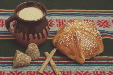 Pan de muerto cortado con taza de cafe, canela y piloncillo en fondo de madera