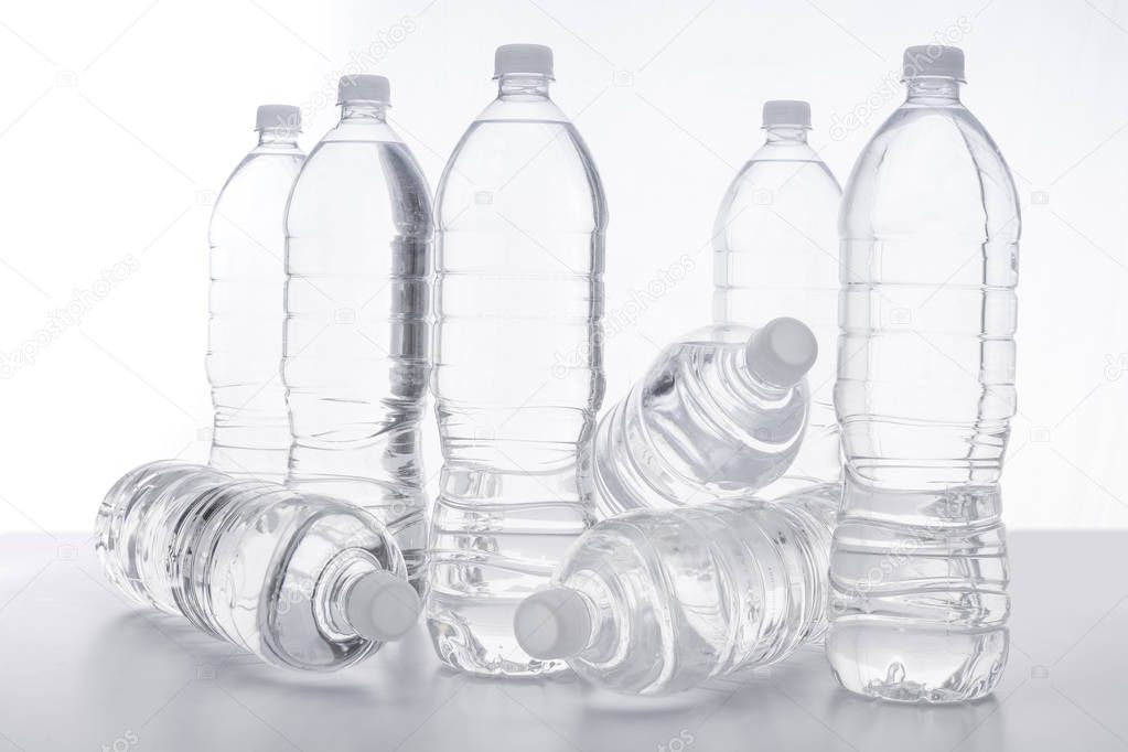 Botellas de agua sobre una mesa con fondo blanco.