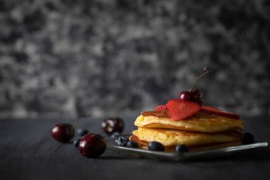 Vişneli çilek ve böğürtlenli sıcak kekler siyah ahşap bir masada. Metin için boşluk