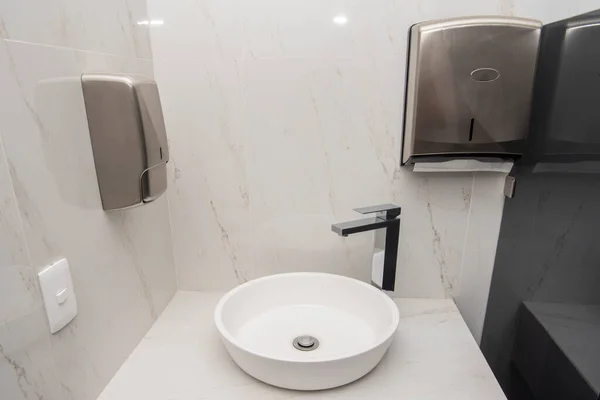 Sink with mixer on a marble base with two dispensers, one for soap and the other for sanitary napkins