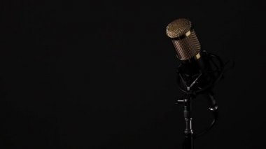 Tabanlı, kablolu, siyah arkaplanı ve hareket eden ışıklandırması olan profesyonel masaüstü mikrofonu..