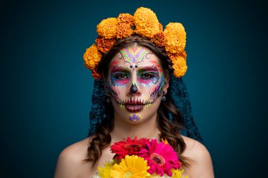 Kafasında ve ellerinde kadife çiçekleri olan Catrina.
