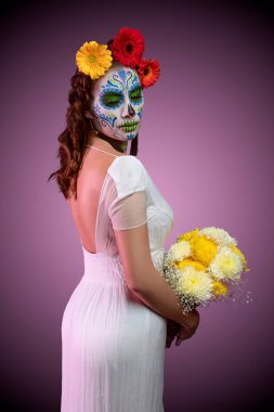 Beyaz elbisesi, çiçekleri ve leylak arkaplanı olan zarif bir kedi.