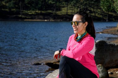 Ormanda koştuktan sonra bir gölün kıyısında dinlenen bir sporcu..