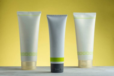 Farklı boyutlarda krem tüpleri ve sarı bir arka plan.