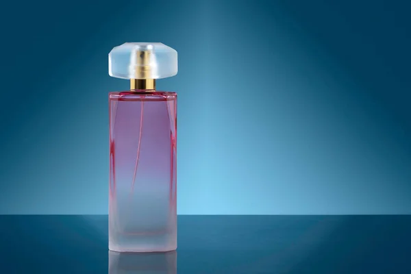 キャップを片側にしたエレガントなピンクの香水瓶と濃いグラデーションの背景 — ストック写真