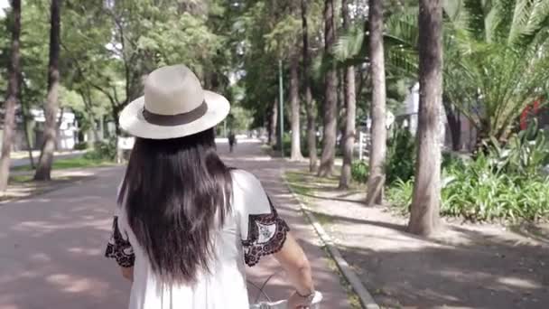 Dziewczyna Białej Sukience Kapeluszu Spaceruje Rowerem Parku Aktywność Świeżym Powietrzu — Wideo stockowe