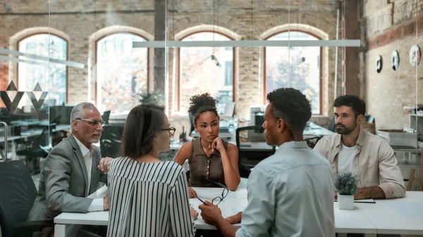 Viktigt möte. Grupp affärsmän diskuterar något och arbetar tillsammans medan de sitter vid kontorsbordet — Stockfoto