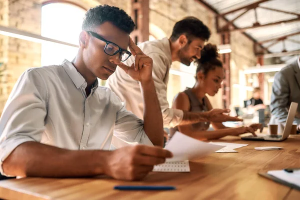 La vie au bureau. Groupe de jeunes gens d'affaires travaillant ensemble tout en étant assis à la table du bureau — Photo