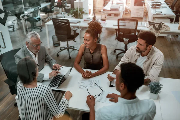 Üzleti megbeszélés. Top view érett férfi formális viselet megvitatása valamit a multikulturális csapat, miközben ül az irodában asztal — Stock Fotó