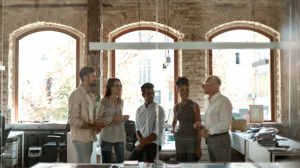 Рабочая группа. Группа современных людей обсуждает что-то на деловой встрече, стоя в современном офисе — стоковое фото