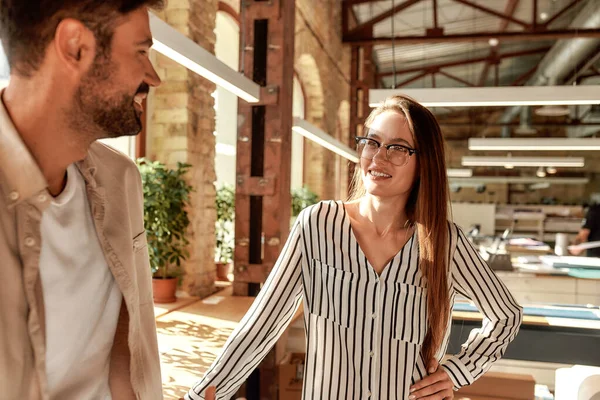 Office life. Two modern young people talking about something while standing in the creative office — Stockfoto