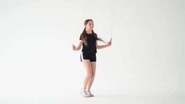 Çocuklar için spor egzersizleri. Güzel ve hareketli bir genç kız eğimli arka planda ip atlıyor. Çocuklar ve spor, aktif sağlıklı çocukluk