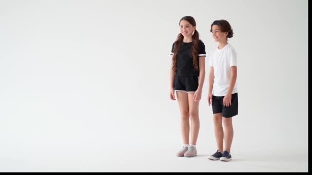 灰色のグラデーションを背景にスポーツをするかわいい子供たち。幸せな十代の女の子と男の子の板運動や笑顔を行うの完全な長さ。子供のためのスポーツ活動,ワークアウト — ストック動画
