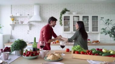 Romantik bir akşam yemeği. Mutlu aile çifti şarap içip, dans edip, eğlenirken modern mutfakta birlikte yemek hazırlıyorlar.