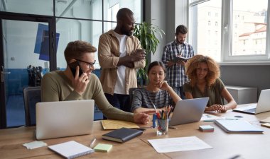 İş yerindeki işadamları. Modern çalışma alanında birlikte çalışırken iletişim kuran, konuşan, yeni fikirleri paylaşan çok ırklı iş arkadaşları grubu.