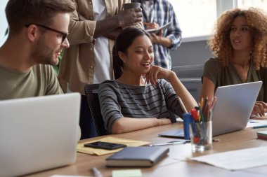 Modern ofiste birlikte çalışan bir grup genç çok kültürlü iş adamı. Başarılı ekip konuşmaları, fikirleri paylaşmaları, birlikte çalışırken projeyi tartışmaları.