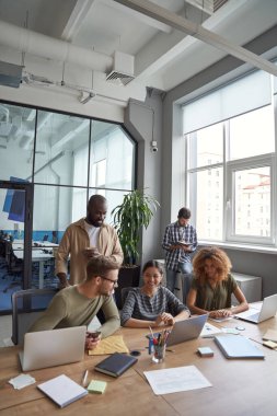 Birlikte çalışma alanında başarılı bir takım. Modern ofiste çalışırken, çok ırklı iş arkadaşlarının iletişim kurduğu, yeni fikirleri paylaştığı dikey bir çekim.