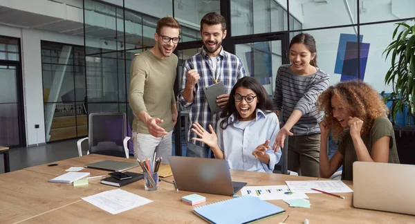 Grandes resultados. Grupo de gente de negocios multicultural feliz mirando la pantalla del ordenador portátil y discutiendo los resultados del proyecto mientras trabajan juntos en la oficina moderna — Foto de Stock