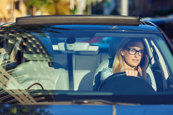 Na cestě do kanceláře. Zaostřené starší obchodní žena nosí brýle mluvit mobilním telefonem s klientem nebo partnerem při řízení auta — Stock fotografie