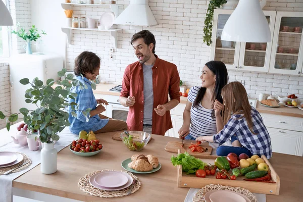 Ebeveynlerle yemek pişirmek. Güzel bir aile salata hazırlıyor, evdeki modern mutfakta birlikte yemek pişiriyorlar. — Stok fotoğraf