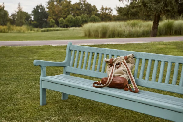 Casual rugzak op de houten bank buiten met groene bomen en gras op de achtergrond — Stockfoto