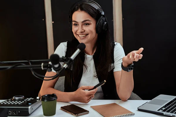 Portait de atraente jovem apresentadora de rádio que parece emotiva enquanto fala em microfone, moderando um show ao vivo — Fotografia de Stock