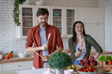Birlikte yemek pişirmek. Mutlu ve güzel bir aile çifti evde, modern mutfakta sağlıklı yemekler hazırlarken eğleniyor ve boş zamanlarının tadını çıkarıyor.