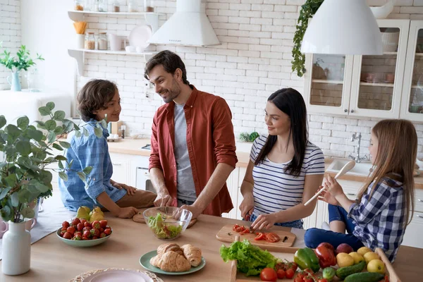Preparando una ensalada. Preciosa familia de cuatro cocinar juntos en la cocina moderna en casa — Foto de Stock