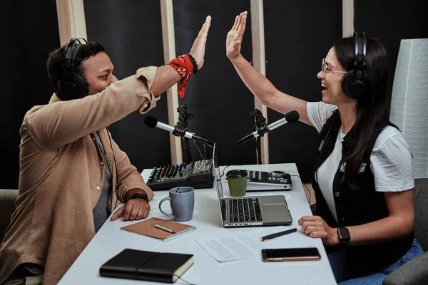 Portait de dos alegres presentadores de radio, hombre y mujer jóvenes dando choco mientras hablan, moderando un espectáculo en vivo en el estudio —  Fotos de Stock