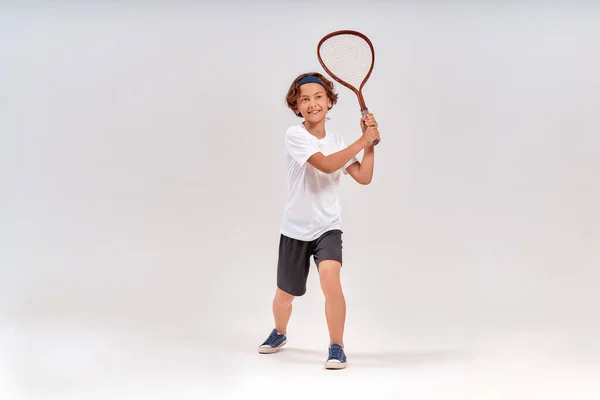 网球很有趣。一个快乐的少年拿着网球拍，在灰蒙蒙的背景下面带微笑，全景全景拍摄 — 图库照片