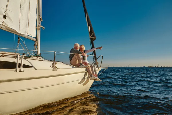 Yelkenli. Mutlu emekli aile fertleri bir yelkenli teknesinde ya da yat güvertesinde, sakin mavi bir denizde, ufukta geziniyor ve günbatımının tadını çıkarıyorlar. — Stok fotoğraf