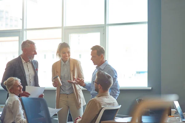 Kraftfullt framgångsrikt team. Grupp av multiraciala affärsmän i klassisk slitage diskuterar arbete och dela idéer när du står i det moderna kontoret eller coorking utrymme — Stockfoto