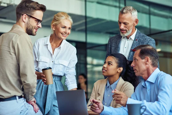 Tener una reunión. Grupo de gente de negocios multirraciales en ropa clásica trabajando juntos en un nuevo proyecto mientras están sentados juntos en la oficina, utilizando el ordenador portátil — Foto de Stock