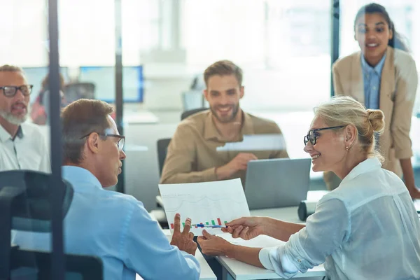 Hermosa mujer de negocios madura y su colega masculino analizando el informe y discutiendo los resultados mientras tiene una reunión con el equipo del proyecto — Foto de Stock