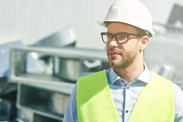 Stock image Portrait of young civil engineer wearing helmet looking away while standing at construction site