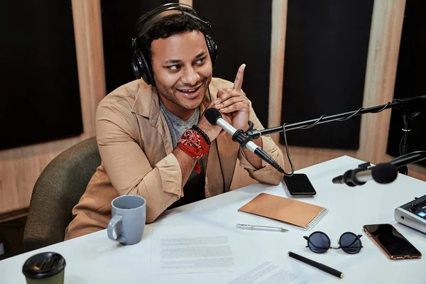 Portrét šťastného mladého mužského rozhlasového moderátora s úsměvem při hovoru, vysílání ve studiu pomocí mikrofonu a sluchátek — Stock fotografie