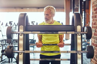 Spor ve vücut geliştirme konsepti. Spor kıyafetli güçlü bir adam spor salonunda ağırlık kaldırırken ya da ağırlık kaldırırken ağırlık çalışırken, ağırlık çalışırken.