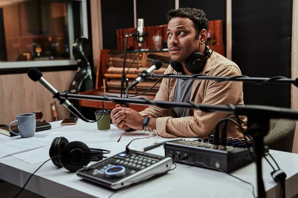 Ritratto di giovane conduttore radiofonico maschile concentrato mentre si prepara a moderare uno spettacolo dal vivo in studio — Foto Stock