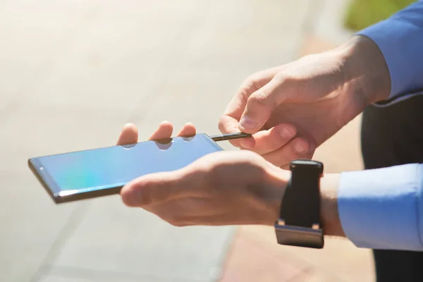 Schnappschuss eines Geschäftsmannes mit Flash-Laufwerk für Smartphone, während er an einem sonnigen Tag im Freien arbeitet, Fokus auf männliche Hände — Stockfoto